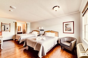 Habitación de hotel con dos camas, una silla, un escritorio, un espejo, un cuadro en la pared y una ventana.
