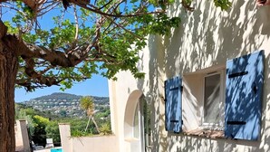 A glass-top table with metal chairs, a pool, and a view of a hillside. - Haven of peace in a villa with pool (Antibes)