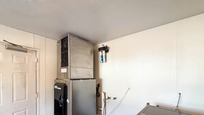 A room with a white door, a black refrigerator, a white wall, and a white ceiling. - Studio 6 Greenville, SC (Greenville)