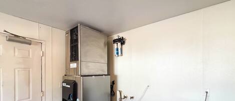 Una habitación con una puerta blanca, un refrigerador negro, una pared blanca y un techo blanco.