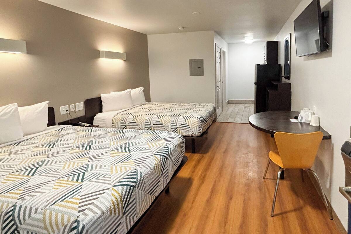 Una habitación de hotel con dos camas, una mesita y un televisor.