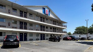 A motel with multiple floors, balconies, and a parking lot with several cars. - Studio 6 Greenville, SC (Greenville)