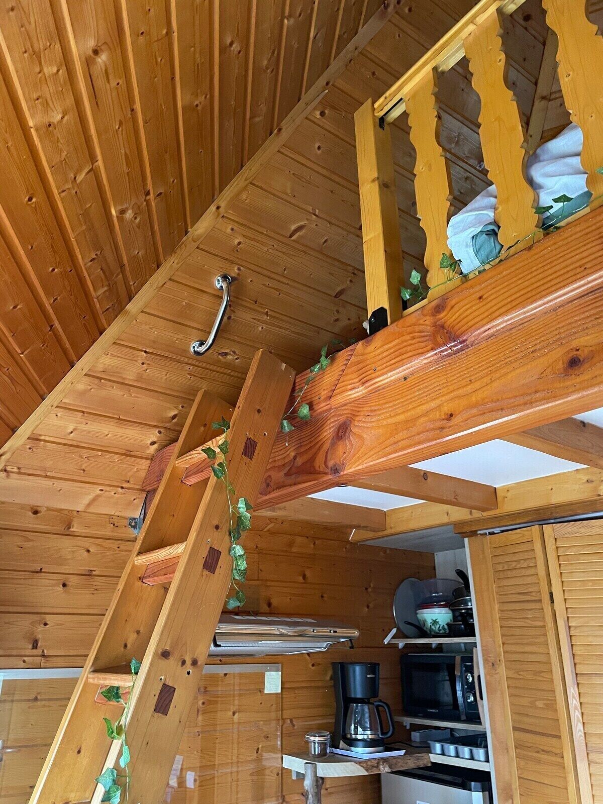 A wooden interior with a kitchen area, including a stove, microwave, and coffee maker.