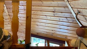 A wooden attic room with a sloped ceiling, a wooden beam structure, and a small window.