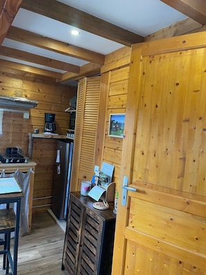 Interior de una cabaña de madera con cocina, una mesa de comedor y un refrigerador.