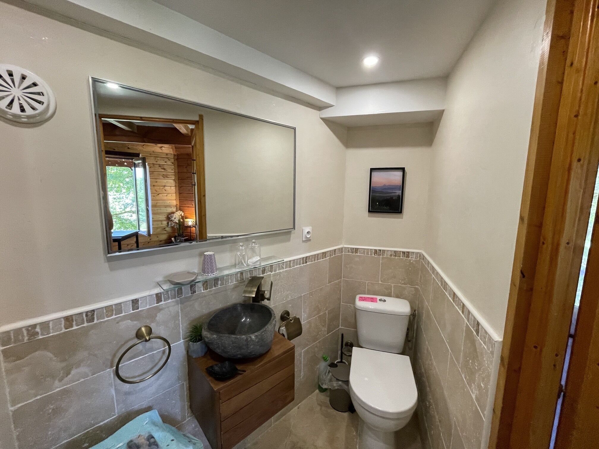 A bathroom with a stone sink, a toilet, and a mirror above the sink.
