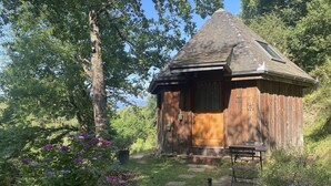 A rustic wooden cabin with a sloped roof, a wooden door, and a small porch with a bench.