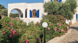 A building with white walls and blue accents, surrounded by greenery and flowers. - Beautiful vacation villa in the heart of Puglia Castellana Grotte (Puglia)