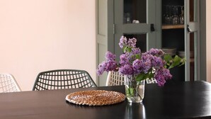 A dining area with a dark wooden table, green chairs, a woven placemat, and a vase with purple flowers. - Beautiful vacation villa in the heart of Puglia Castellana Grotte (Puglia)
