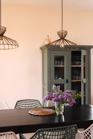 A dining area with a dark wooden table, green chairs, a woven placemat, and a vase with purple flowers. - Beautiful vacation villa in the heart of Puglia Castellana Grotte (Puglia)