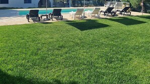 A pool area with lounge chairs, umbrellas, and a building in the background. - Beautiful vacation villa in the heart of Puglia Castellana Grotte (Puglia)