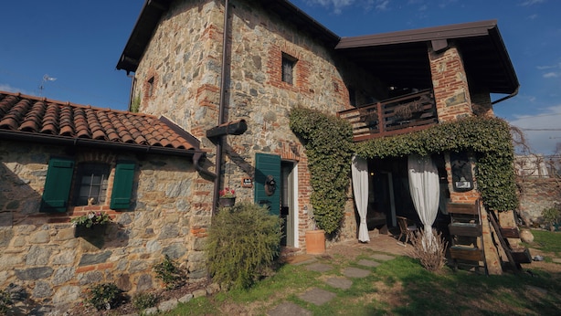 A stone building with a balcony, a wooden staircase, and a door with a green shutter. - The Willow Bed & Breakfast - Room Sage (Veruno)