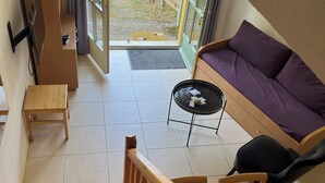 Ein modernes Interieur mit einer Holztreppe, einem Sofa, einem kleinen Tisch und einem an der Wand befestigten Fernseher.