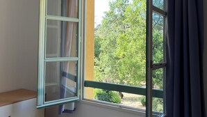Ein Zimmer mit großem Fenster, Heizkörper und einem Bett.