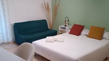 Una habitación de hotel con cama, escritorio, silla, mesita de noche y ventilador de techo.
