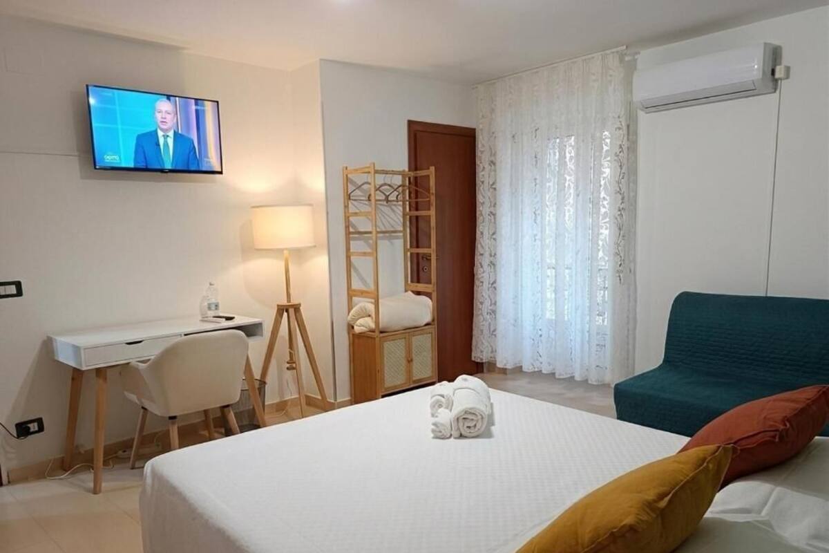 Une chambre d’hôtel avec un lit, un bureau, une chaise, une t élévision et une fenêtre avec des rideaux.