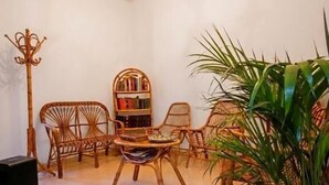A room with a chandelier, wicker furniture, a bookshelf, and a potted plant. - Guest House San Giorgio (Caltagirone)