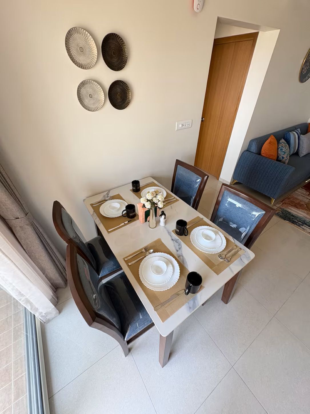 A dining area with a table set for four, chairs, a coffee machine, and wall decor.