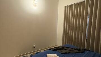A hotel room with a bed, a ceiling fan, and a wall-mounted light fixture.