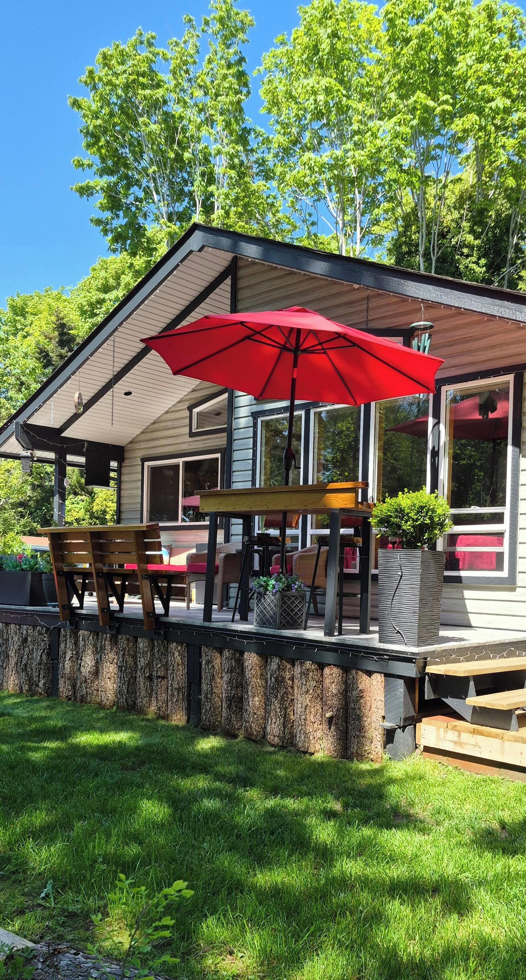 A house with a covered patio, outdoor seating, and a red umbrella.