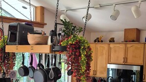 Une cuisine moderne avec un îlot central, des ustensiles de cuisine suspendus et des tabourets de bar.