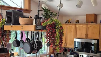 Une cuisine moderne avec un îlot central, des ustensiles de cuisine suspendus et des tabourets de bar.