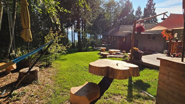 Une terrasse en bois avec un foyer, un hamac et une petite table.