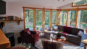 Un salon chaleureux avec une cheminée, de grandes fenêtres et un coin salon confortable.