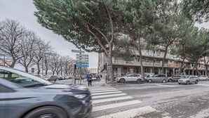 Katunäkymä, jossa on suojatie, parkkeerattuja autoja ja parvekkeellinen rakennus.