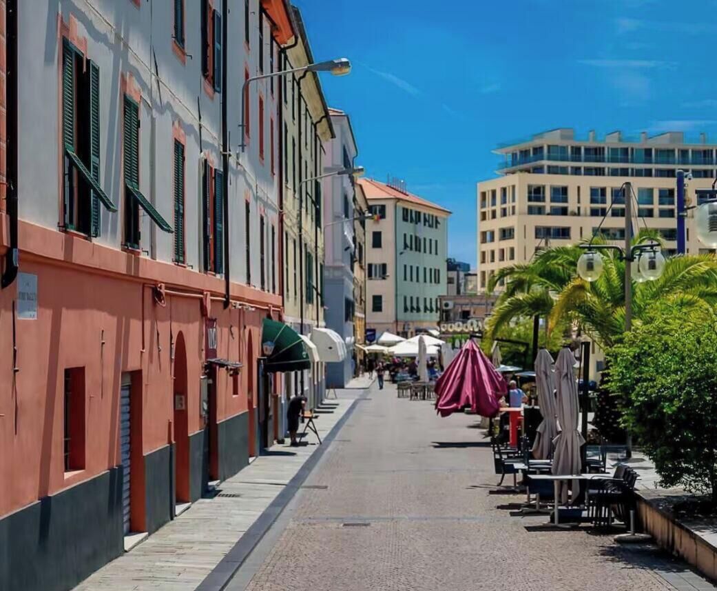 Een straat met gebouwen, terrasjes en een heldere lucht.