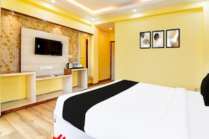 A hotel room with a bed, a TV mounted on the wall, a desk, and a chair. - Classic With Balcony Rosedale Reliance Guest House (Barasat)