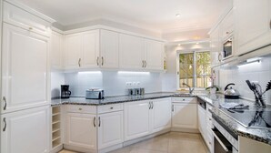 A modern kitchen with white cabinetry, granite countertops, and stainless steel appliances. - Apartment 'Tulipa' with Private Pool, Wi-Fi, and Air Conditioning (Almancil)