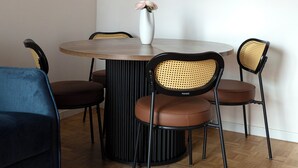 Ein Essbereich mit einem runden Tisch, vier Stühlen, einer Blumenvase und einem gerahmten Bild an der Wand.