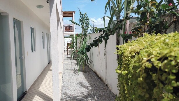 A narrow corridor with doors on one side and a wall with plants on the other. - Hotel Barra de São Miguel (Barra de São Miguel)