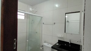 A bathroom with a glass shower enclosure, a toilet, a sink with a black countertop, and a mirror. - Hotel Barra de São Miguel (Barra de São Miguel)