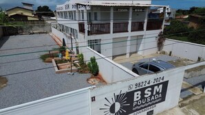 A two-story building with 'Pousada BSM' signage, a gated parking area, and a small garden. - Hotel Barra de São Miguel (Barra de São Miguel)