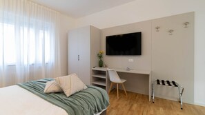 A bedroom with a bed, a desk, a chair, a TV, and a small stool. - Narea 15 - [3 min from Arena & Piazza Bra] (Verona)