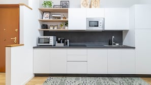 Eine moderne Küche mit weißen Schränken, einer Mikrowelle, einem Toaster und einem Spülbecken.