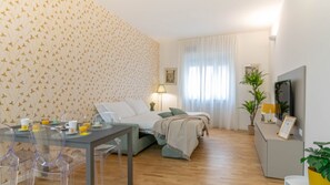 Ein Schlafzimmer mit Bett, Nachttisch, Lampe und einem Fenster mit Vorhängen.