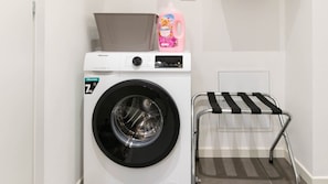 A white Hisense washing machine with a 7kg capacity, a pink bottle of Coccinello laundry detergent, and a metal drying rack with black straps. - Narea 15 - [3 min from Arena & Piazza Bra] (Verona)