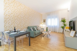 A living room with a dining area, a sofa, a coffee table, and a TV stand. - Comfortable Leoncino for up to 4 guests (Verona)