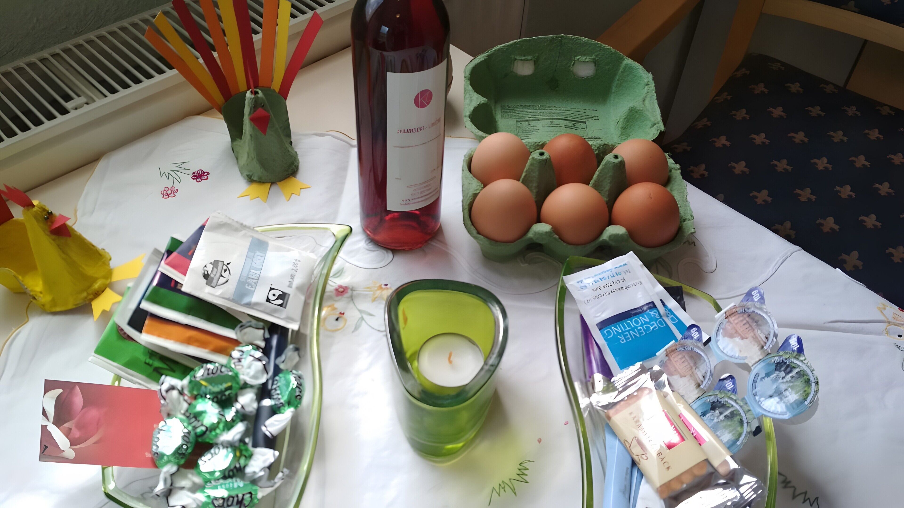 Ein Tisch mit einer Flasche, Eiern, einer Kerze und verschiedenen verpackten Gegenständen.