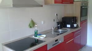 Eine moderne Küche mit Spüle aus Edelstahl, einer Kaffeemaschine und roten Schränken.