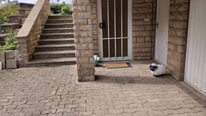 A stone staircase leading to a door with a metal gate, a small porch area with a doormat, and a stone wall. - Apartment "For 4 Guests, 75 m²" with Shared Garden and Wi-Fi (Heeßen)