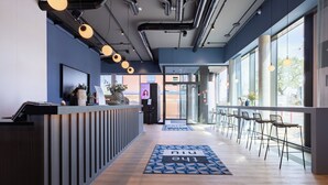 A modern reception area with a reception desk, a digital screen, and a seating area with chairs and tables.