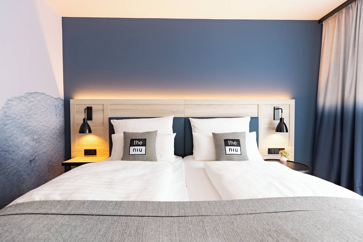 Une chambre d’hôtel avec un grand lit, deux tables de chevet avec des lampes et une tête de lit au motif dégradé.