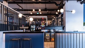 A modern bar area with stools, a neon sign, and a counter with a coffee machine.