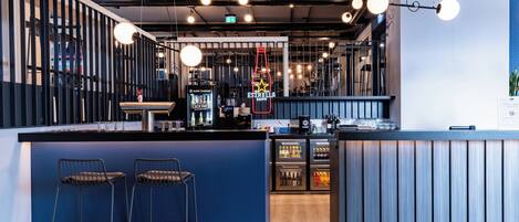 A modern bar area with stools, a neon sign, and a counter with a coffee machine.