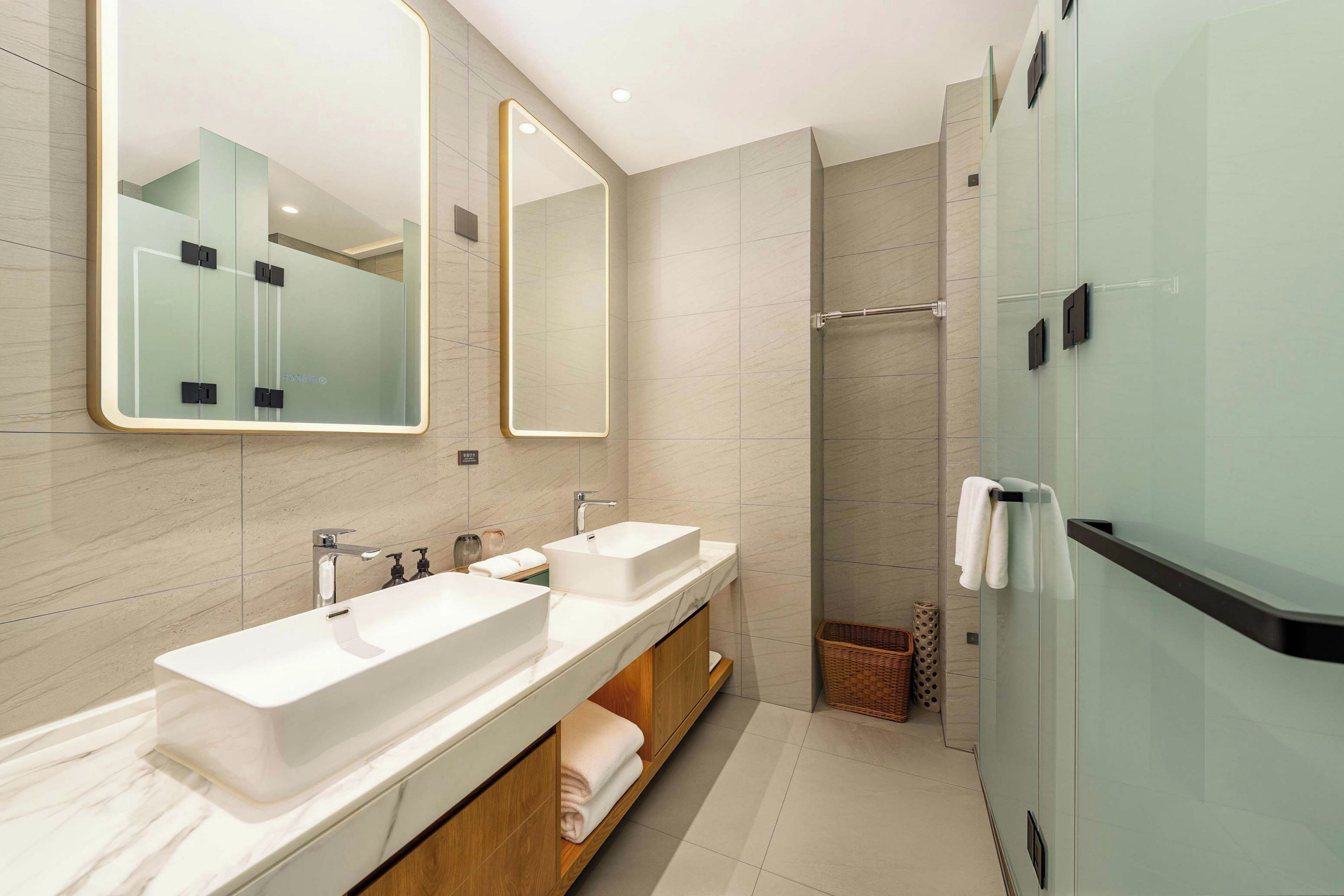 Un baño moderno con dos lavamanos, un espejo grande y una cabina de ducha de vidrio.