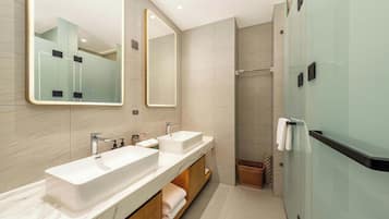 Un baño moderno con dos lavamanos, un espejo grande y una cabina de ducha de vidrio.